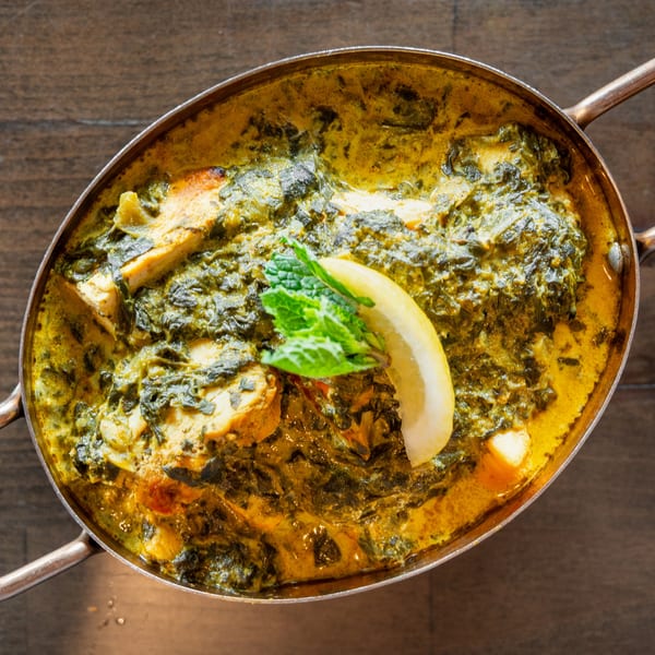 Palak Paneer, a creamy spinach and cheese curry, garnished with a lemon wedge and mint.