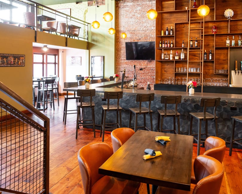 A restaurant interior with a bar, high-top tables, and a mezzanine level with additional seating.